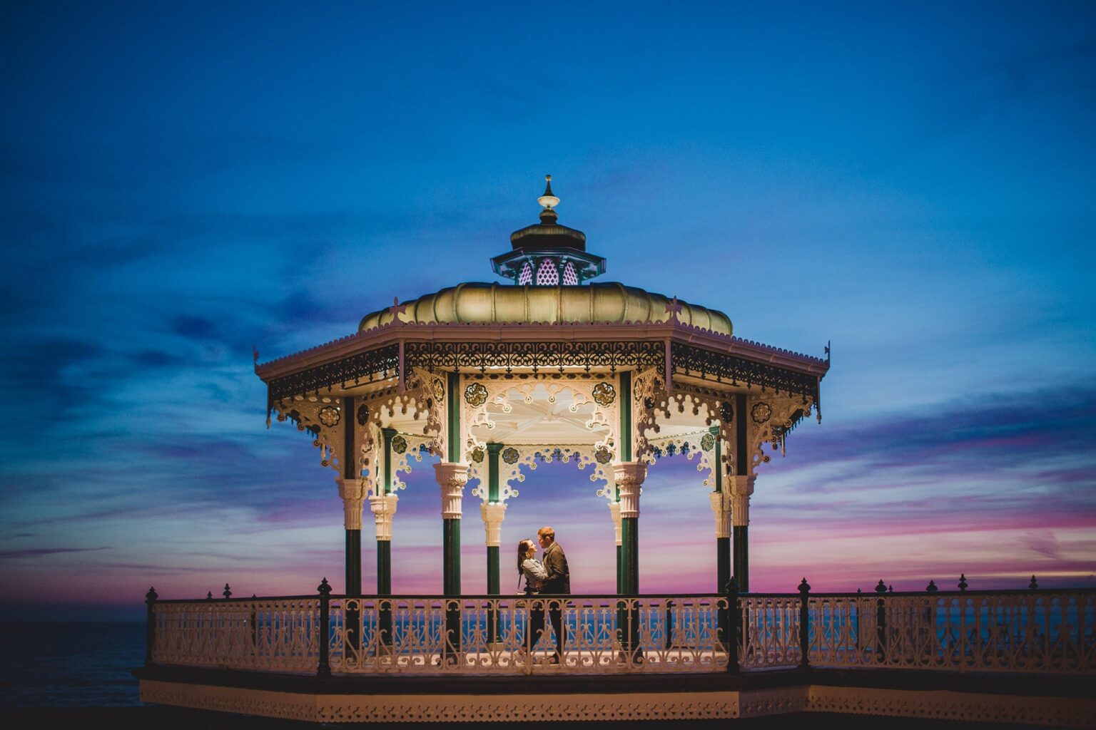 Couple hug and kiss at the bandstand in Brighton.