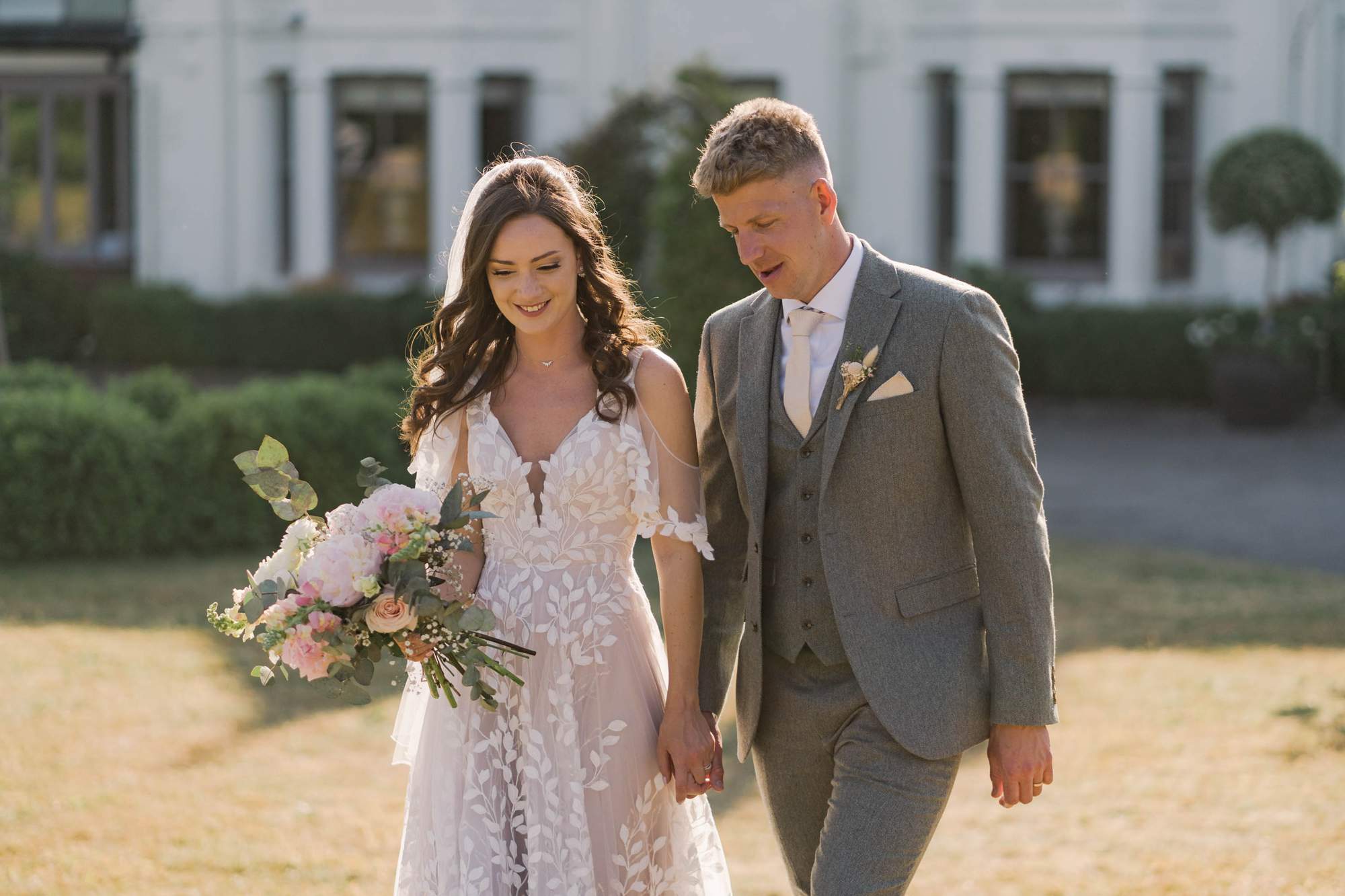 Bride and groom smiling whilst they take a stroll on their wedding day in the Summer.