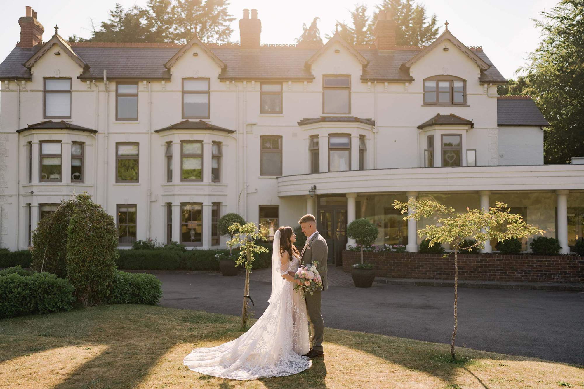 Bride and groom stare lovingly in to each other's eyes on their wedding day with Southdowns Manor in the background.